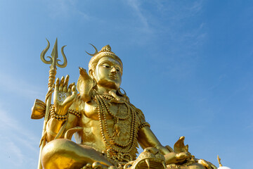 Fototapeta premium Golden Shiva statue with blue sky, Big statue hindu god and spiritual landmark in Thailand