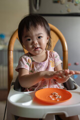 Adorable baby girl is reaching for the camera with a playful expression on her face