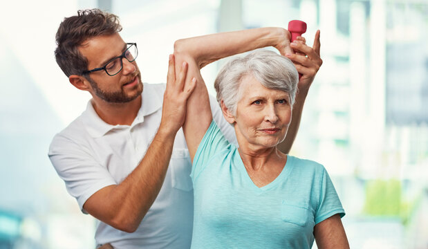 Dumbbells, physiotherapist and senior woman with stretching, rehabilitation or recovery. Healthcare, weights and physical therapist with elderly patient for arm exercise for muscle training in clinic