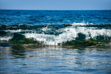 Glowing sea waves shimmer in daylight. Ocean wave rise high. Bright sea waves background. Blue green sea waves patterns. Sea waves of nature.