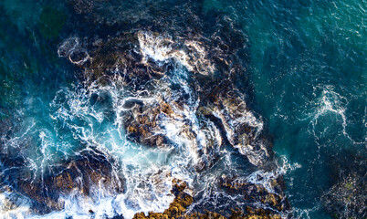 Turquoise water with reef. Blue ocean water. Coastline from above. Summer beach with crashing waves. Dramatic coastline. Ocean surface. Rocky coast with sea foam. Wave moving. © Volodymyr