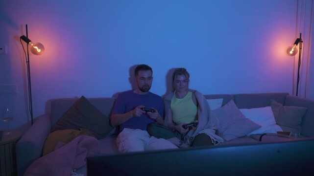 Couple Playing Video Games Together in Cozy Living Room at Night