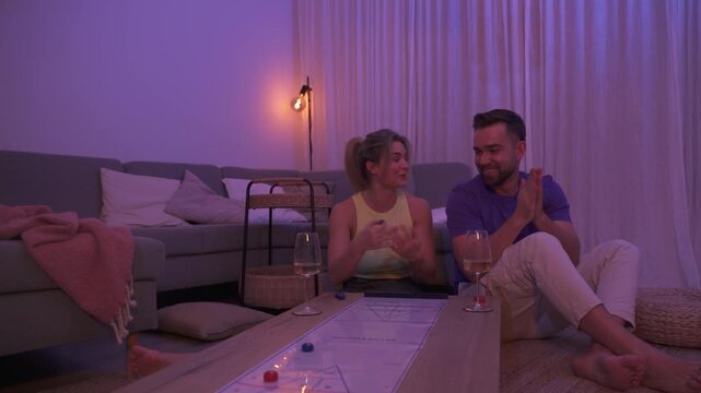 Couple Playing Table Shuffleboard at Home During Cozy Evening with Wine