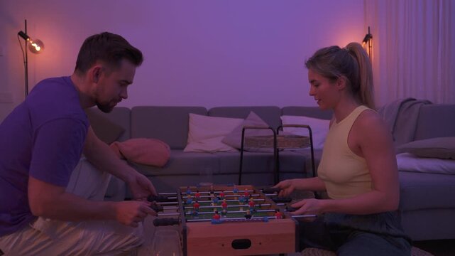 Happy Couple Playing Tabletop Foosball Together in Cozy Living Room