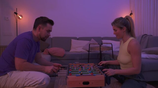 Happy Couple Playing Tabletop Foosball Together in Cozy Living Room