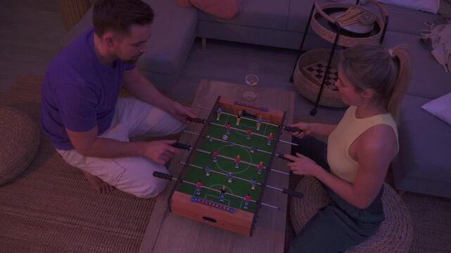Happy Couple Playing Tabletop Foosball Together in Cozy Living Room
