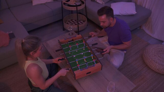 Happy Couple Playing Tabletop Foosball Together in Cozy Living Room