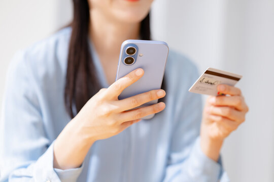 クレジットカードを見ながらスマホを操作する女性