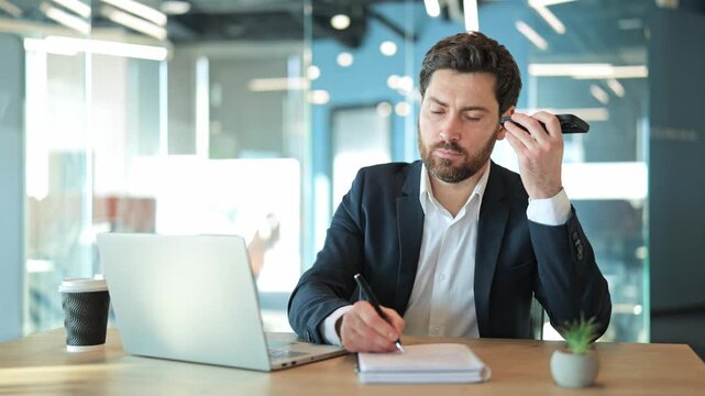 Focused professional at desk, receiving phone message, diligently recording notes. Engaged communication, efficient task management in modern workspace. Concentration, productivity, business acumen.