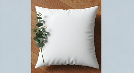 White Square Pillow with Eucalyptus Leaves on Wooden Surface in Soft Lighting