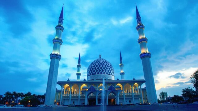 Panoramic view of a white mosque with blue dome and minarets at dusk with cloudy sky