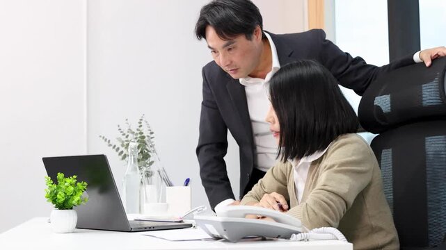 Asian Business Manager and Employee Collaborating on Laptop in Modern Office