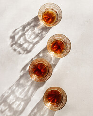 Crystal Whiskey Glasses with shadows at sunlight on beige textured background, minimal aesthetic flat lay  shiny glasses, sun glare, stong alcohol drink concept, summer still life top view, copyspace