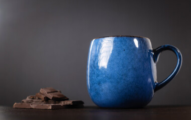A cup of delicious, aromatic coffee with chocolate pieces on a dark background