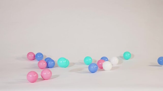 Colorful Plastic Balls Falling and Bouncing on a White Surface