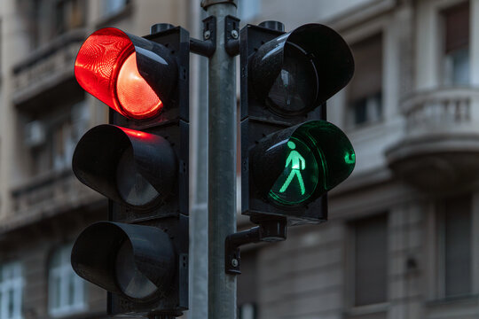 Urban traffic signal system with red vehicle light and green pedestrian crossing signal, managing movement at an intersection.