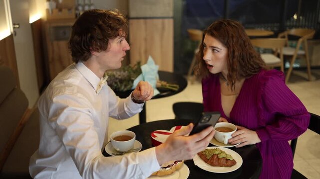 Man shows shocking news on his phone during cafe date revealing something he learned about the woman her stunned reaction creates sudden tension surprise and rising emotion