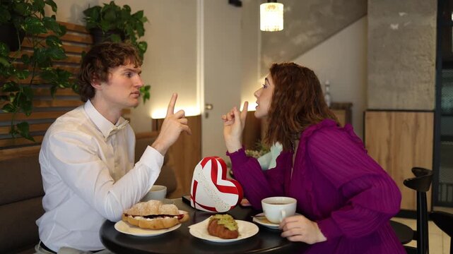 Man leans in during cafe date sharing a quiet secret while signaling to keep it locked woman listens closely amused and curious playful mood intimate moment between two people