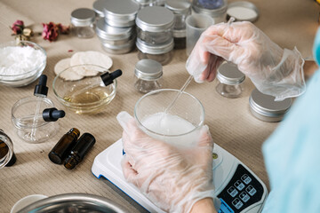 Person uses glass rod to stir white liquid in glass beaker on digital scale. Molecular skincare formulation, active ingredient dissolving, functional beauty craft, precision cosmetic measurement.