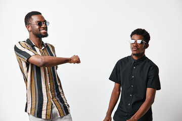 Two African American men with dark skin wearing sunglasses greeting each other with elbow bump on white background. Casual style, friendship and social interaction concept. © SHOTPRIME STUDIO