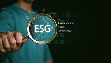 Business professional presenting ESG concept with green globe and magnifying glass, symbolizing environmental, social and governance strategy, sustainable investment.
