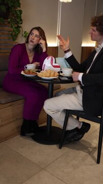 Vertical screen girl sits on a date lost in her own thoughts while the guy keeps talking creating a distant mood as she drifts away mentally thinking about something completely different