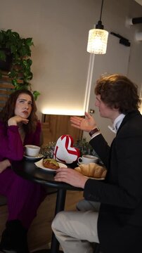 Vertical screen girl sits bored during another cafe date showing clear disinterest while the man keeps talking creating an awkward moment of mismatched energy and fading connection at the table