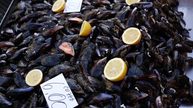 Fresh mussels displayed on a market counter with sliced lemons creating a vibrant coastal food atmosphere and showcasing the texture color and freshness of local seafood