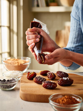 Hands decorating stuffed dates with chocolate in cozy kitchen for culinary blog and dessert tutorial, stuffed dates, date snickers, nut butter filling, healthy dessert, no bake sweet, bite size treat
