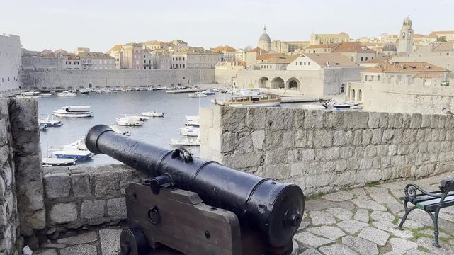 View overlooking Dubrovnik West Harbour, City Walls and iconic terracotta rooftops lit up by golden hour sunrise [cinematic travel clip]