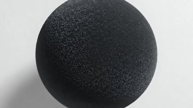 A single dark circle rests on a textured white surface, casting a subtle shadow