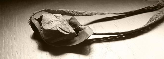 Sling with stone on wooden background