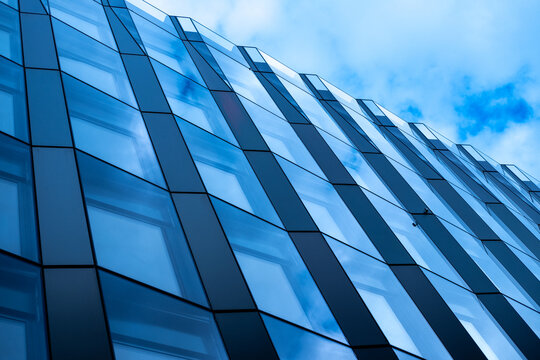 Architecture building facade captures modern glass reflection with windows blue sky and repeating pattern offering copyspace for brochures