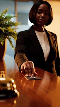 Businesswoman slides keycard on hotel desk during check-in service. Woman provides keycard at reception counter. Professional at hotel desk with keycard. Reception service with businesswoman sliding
