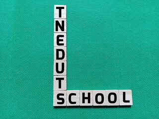 Obraz premium Alphabet letters with the words SCHOOL and STUDENT in a crossword puzzle on a green background. Photo concept about education.