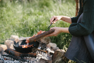 Fototapeta premium Person cooking meat outdoors on open fire