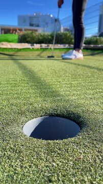 Golf player hitting a golf ball, vertical video. Mini golf
