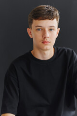 Fototapeta premium Young person sitting in front of dark background with calm expression