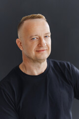 Fototapeta premium Portrait of a man with short hair smiling against a dark background
