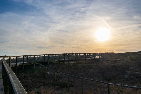 Wooden walkway crossing protected dune area in warm evening light, Portugal, Ovar &ndash; Furadouro, 14 October 2025