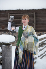 Latvian woman in traditional dress poses in a village in winter. Riga, Latvia.