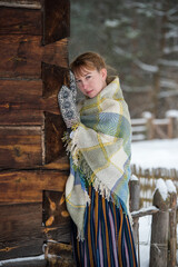 Latvian woman in traditional dress poses in a village in winter. Riga, Latvia.
