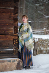 Latvian woman in traditional dress poses in a village in winter. Riga, Latvia.