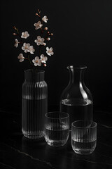 Elegant Glass Vase and Decanter Set with Cherry Blossom Branch on Black Marble Background.