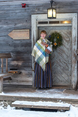 Latvian woman in traditional dress poses in a village in winter. Riga, Latvia.
