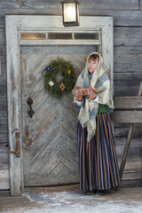 Latvian woman in traditional dress poses in a village in winter. Riga, Latvia.