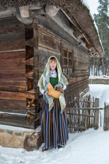 Latvian woman in traditional dress poses in a village in winter. Riga, Latvia.