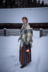 Latvian woman in traditional dress poses in a village in winter. Riga, Latvia.