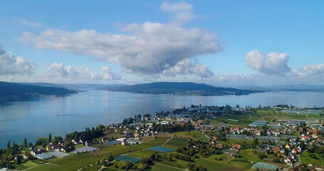 Sky view of a lake area with homes and fields near the water in Switzerland during a sunny day in summer