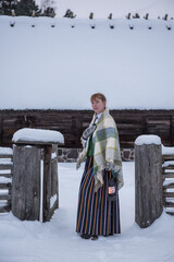 Latvian woman in traditional dress poses in a village in winter. Riga, Latvia.